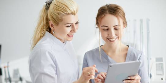 Zahnärztin und Helferin arbeiten am Tablet